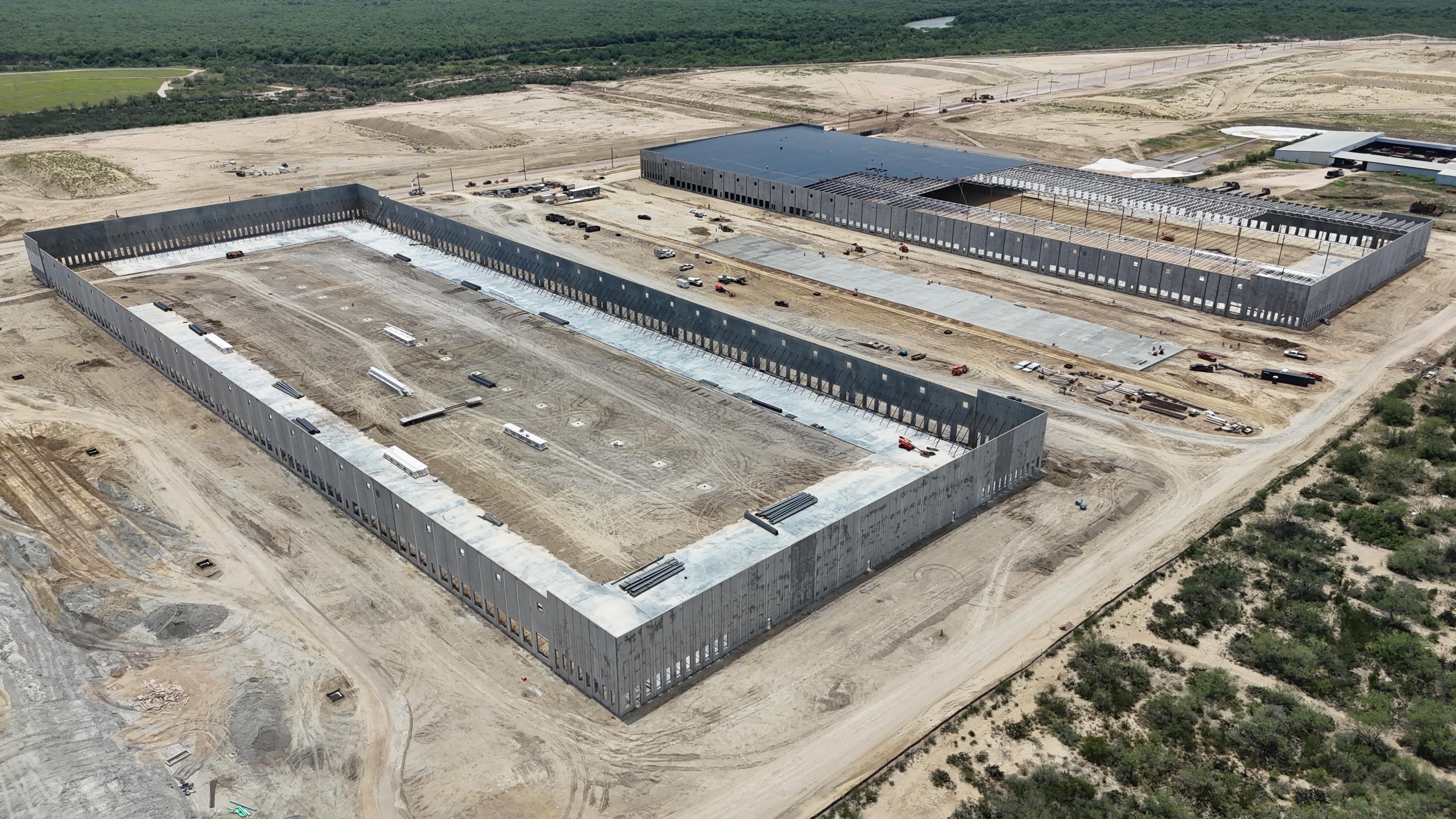 Aerial view of a tilt-wall warehouse shell with interior slab-on-grade placement underway